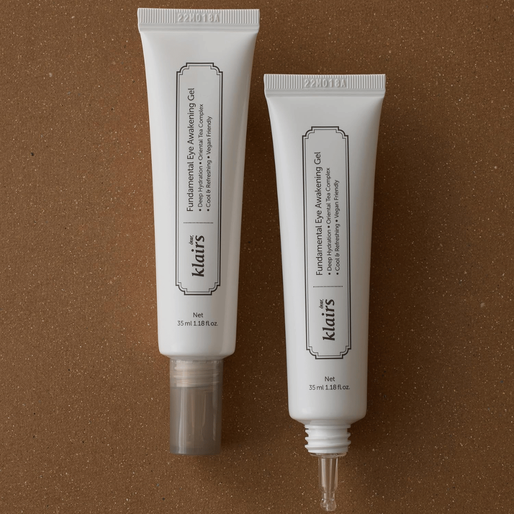 Produktna slika, ki prikazuje Klairs Fundamental Eye Awakening Gel v dveh različicah – zaprto tubo in odprto tubo, ki poudarja ozko konico aplikatorja. Embalaža ima minimalističen bel dizajn in izpostavlja osredotočenost izdelka na vlaženje, hladilen občutek in osvežilno nego predela oči.