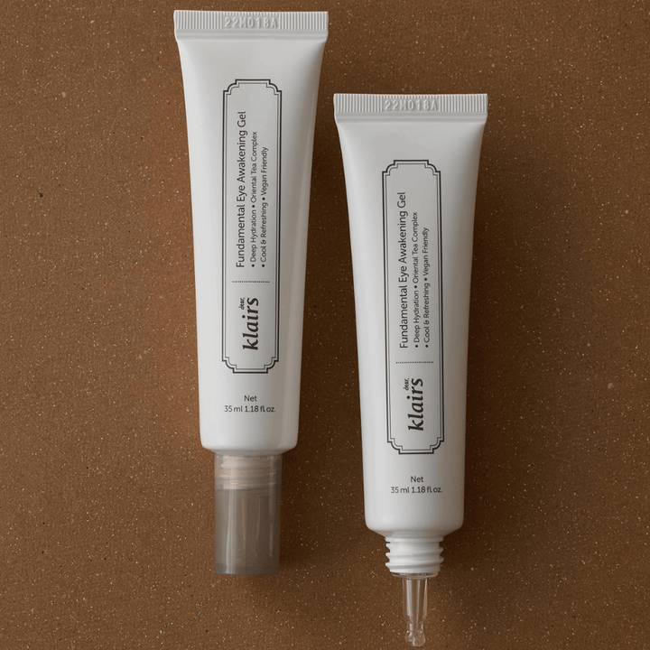 Produktna slika, ki prikazuje Klairs Fundamental Eye Awakening Gel v dveh različicah – zaprto tubo in odprto tubo, ki poudarja ozko konico aplikatorja. Embalaža ima minimalističen bel dizajn in izpostavlja osredotočenost izdelka na vlaženje, hladilen občutek in osvežilno nego predela oči.
