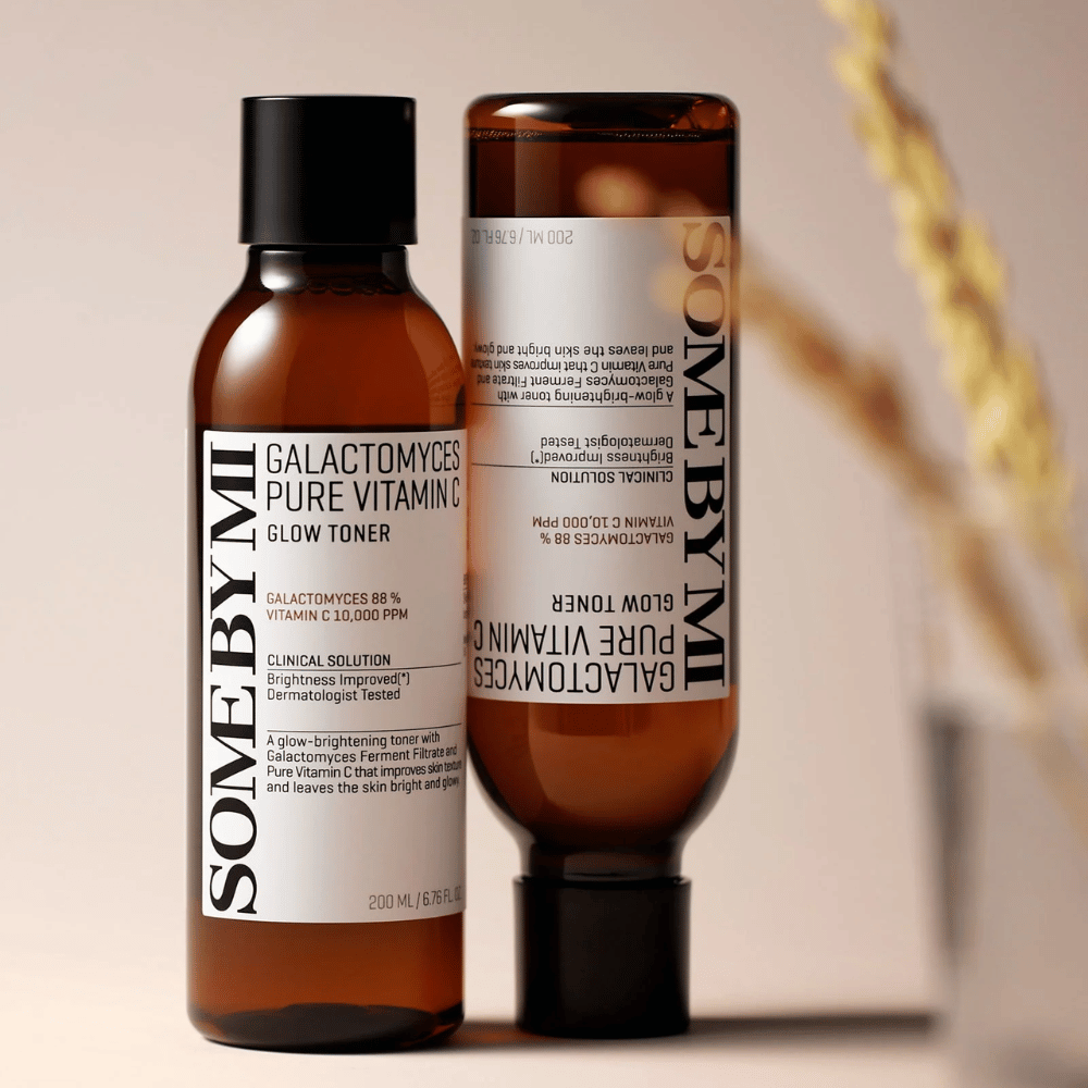 Slika SOME BY MI Galactomyces Pure Vitamin C Glow Toner. Stekleničke so v elegantnem dizajnu z rjavimi toni in črnim pokrovčkom. Izdelek vsebuje 88% galactomyces in 10.000 ppm vitamina C, kar obljublja izboljšanje sijaja kože in svežji ten kože.