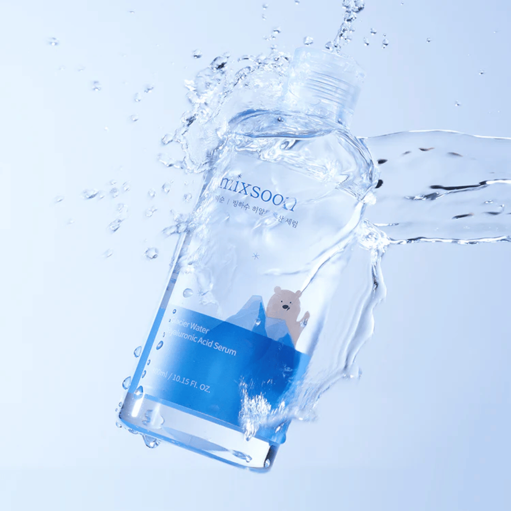 Steklenička Mixsoon Glacier Water Hyaluronic Acid Serum z modro etiketo in motivom polarnega medveda, obdana s pljuskanjem vode na svetlo modri podlagi.
