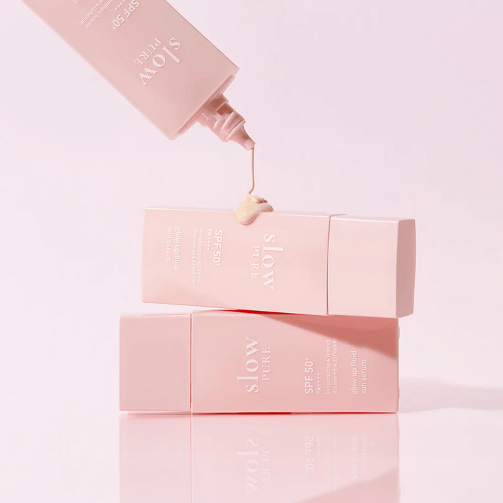 Slow Pure Glow Up Fluid Sun Serum s kremo, iztisnjeno iz stekleničke, prikazuje lahko in negovalno konsistenco.