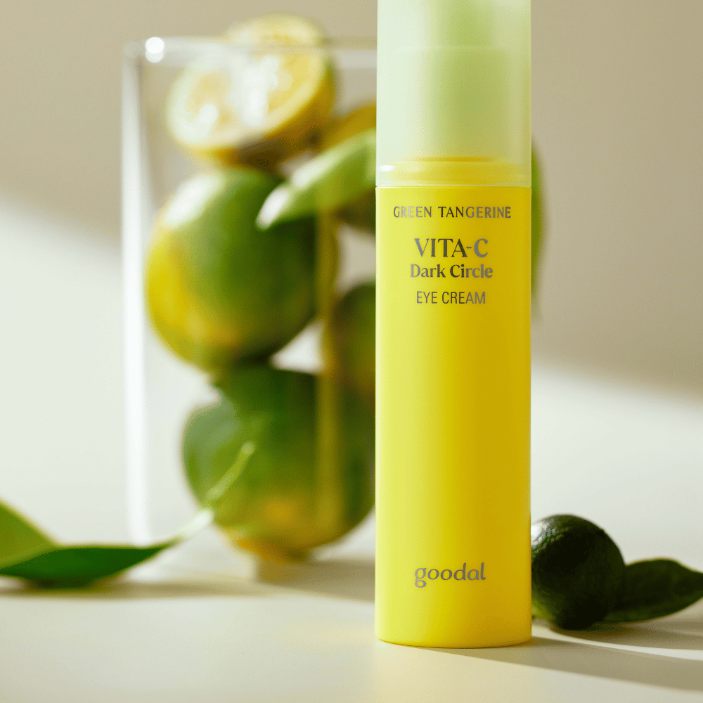 Steklenica Goodal Green Tangerine Vita C Dark Circle Eye Cream 30ml na mizi poleg limete.