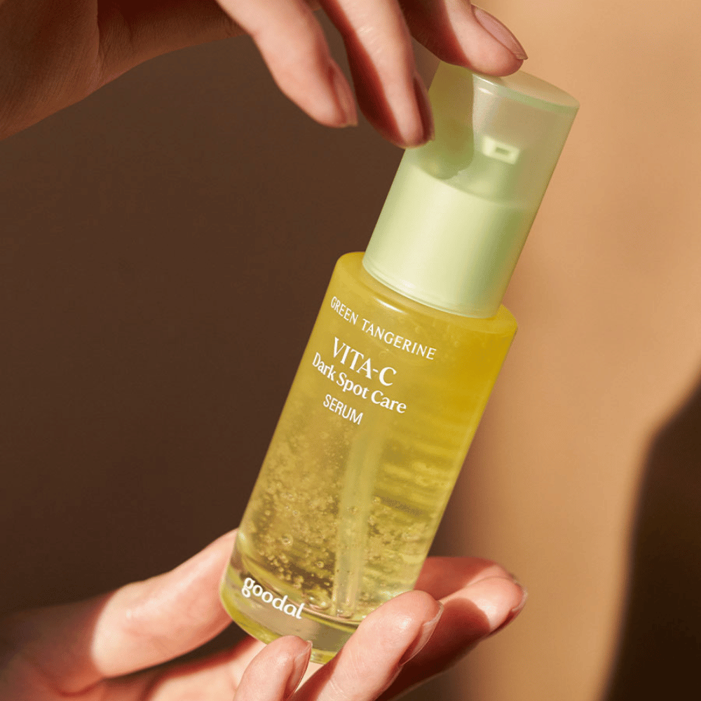 Oseba, ki drži stekleničko Green Tangerine Vita C Dark Spot Care Serum 40ml od Goodal za hiperpigmentacijo in nego temnih madežev.