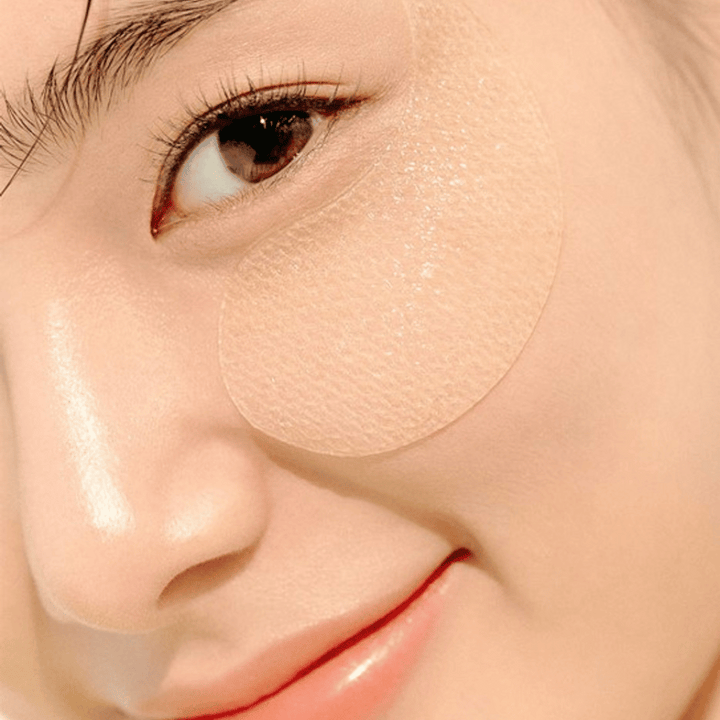 Bližnji posnetek ženskega očesa z vlažilno očesno masko, nameščeno pod njim.