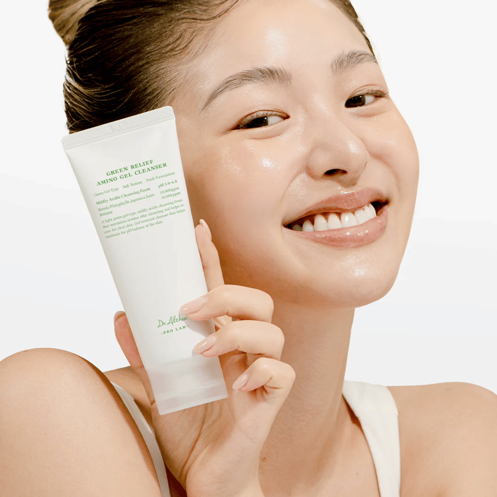 Ženska s sijočo kožo drži Dr. Althea Green Relief Amino Gel Cleanser – vegansko čistilo za občutljivo in razdraženo kožo.