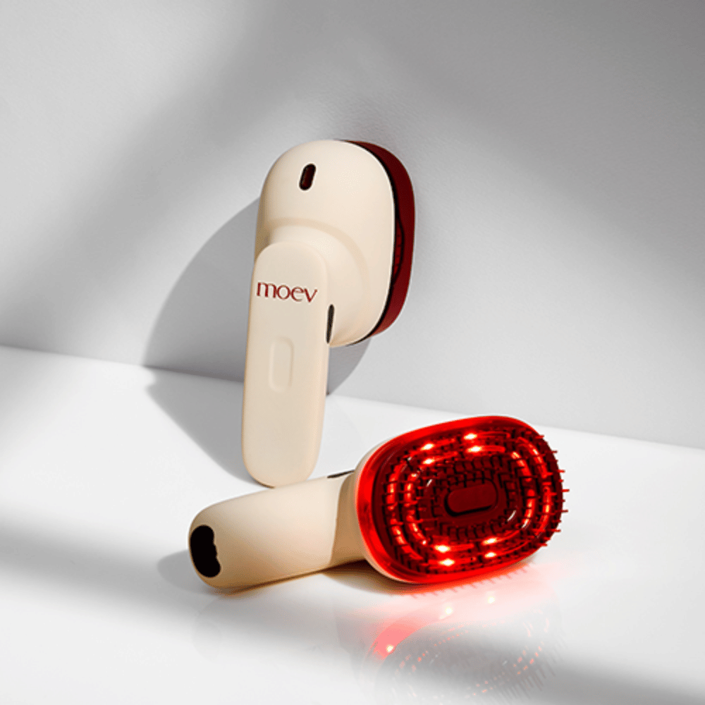 Dva MOEV Hair Steamer Pro na beli podlagi. Ena prikazuje aktivirane rdeče LED-luči, ki stimulirajo lasišče in izboljšujejo rast las.