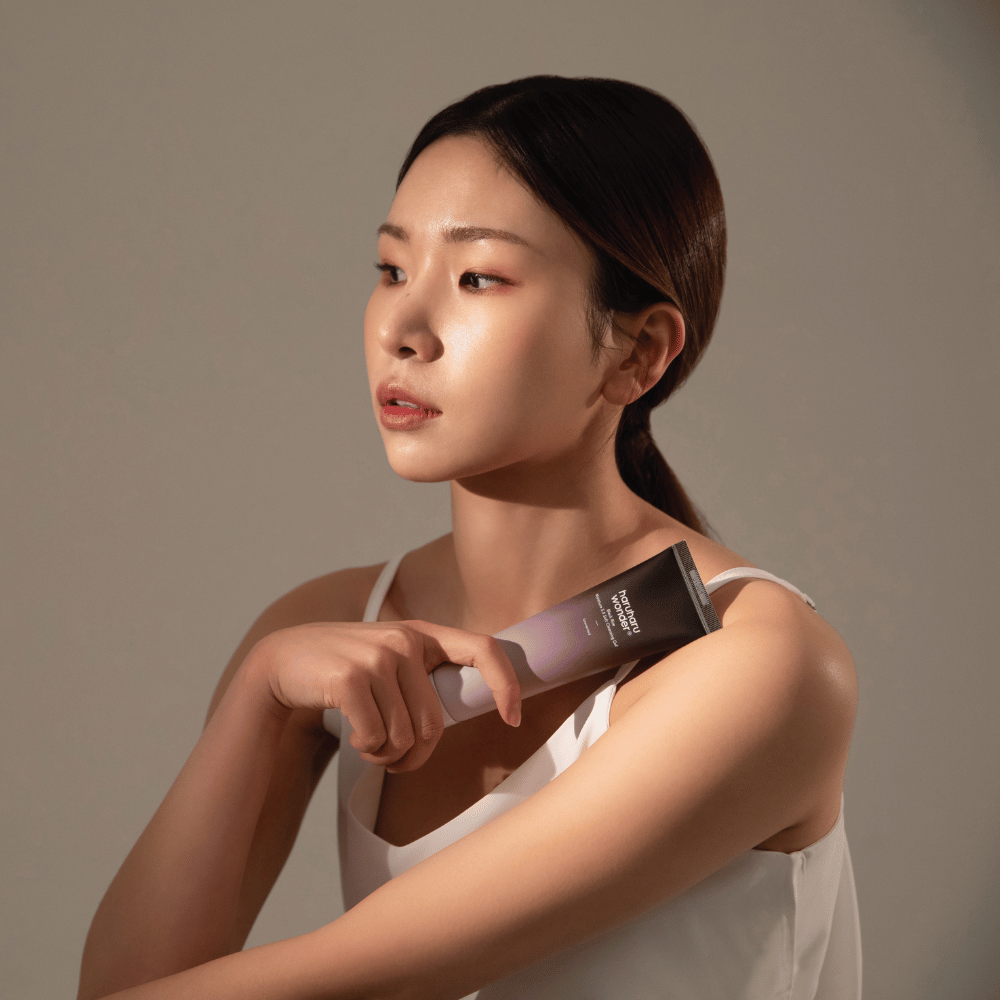 Mlada azijska ženska, ki drži čopič v roki, medtem ko uporablja Haruharu Wonders Black Rice Moisture 5.5 Soft Cleansing Gel 100ml.