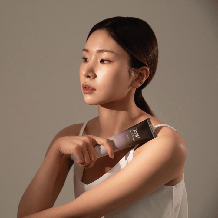 Mlada azijska ženska, ki drži čopič v roki, medtem ko uporablja Haruharu Wonders Black Rice Moisture 5.5 Soft Cleansing Gel 100ml.