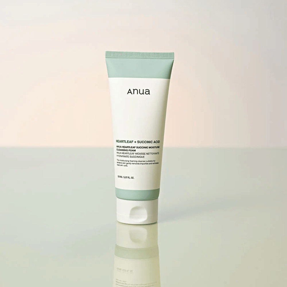 Samostojna slika izdelka Anua Heartleaf + Succinic Acid Moisture Cleansing Foam. Izdelek je prikazan stoječ na odsevni površini, ki jasno poudari dizajn embalaže in elegantno estetiko blagovne znamke.