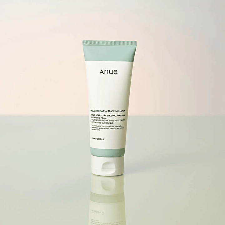 Samostojna slika izdelka Anua Heartleaf + Succinic Acid Moisture Cleansing Foam. Izdelek je prikazan stoječ na odsevni površini, ki jasno poudari dizajn embalaže in elegantno estetiko blagovne znamke.