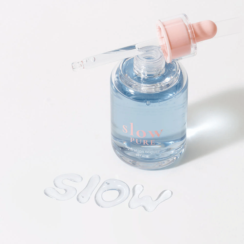 Slow Pure Hydration Texture Serum z odprto pipeto, besedilo napisano v serumu na površini: "Slow".