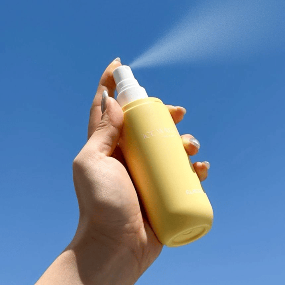 ELROEL Ice Water Sun Mist SPF 40 PA+++ sončna meglica se razprši iz stekleničke proti modremu nebu, lahka zaščita pred soncem, ki vlaži in osveži kožo