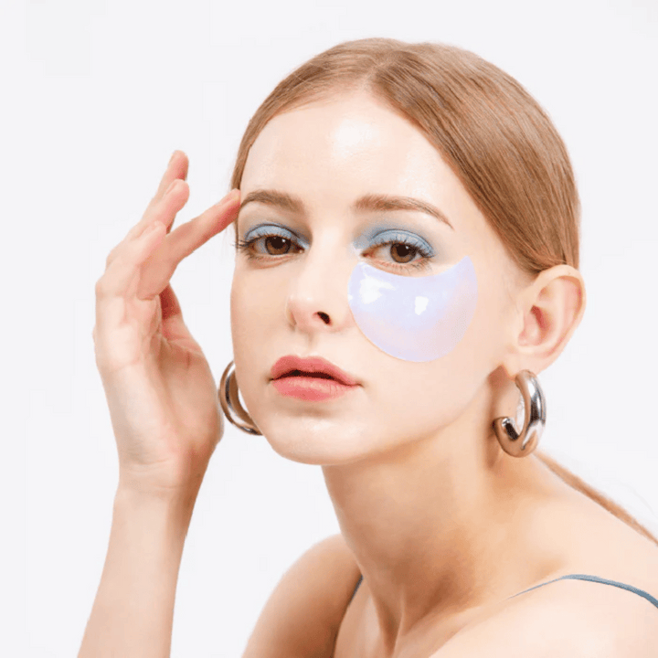 Model nosi modro bleščeč hidrogelni obliž pod očesom za osvežujoč učinek.