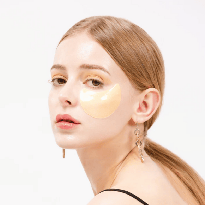 Model nosi zlato bleščeč hidrogelni obliž za oči pod očesom za sijajni učinek.