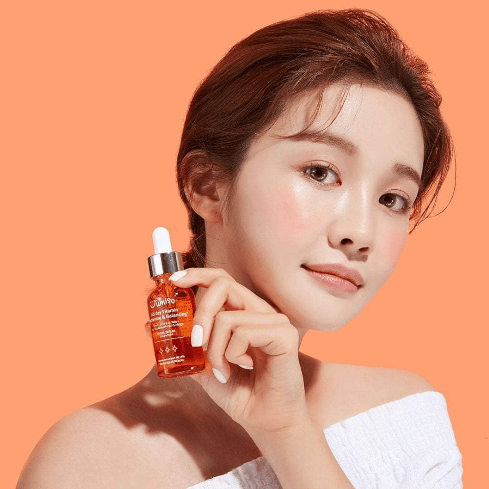 Ženska, ki drži stekleničko JUMISO All Day Vitamin Brightening & Balancing Facial Serum 30ml.