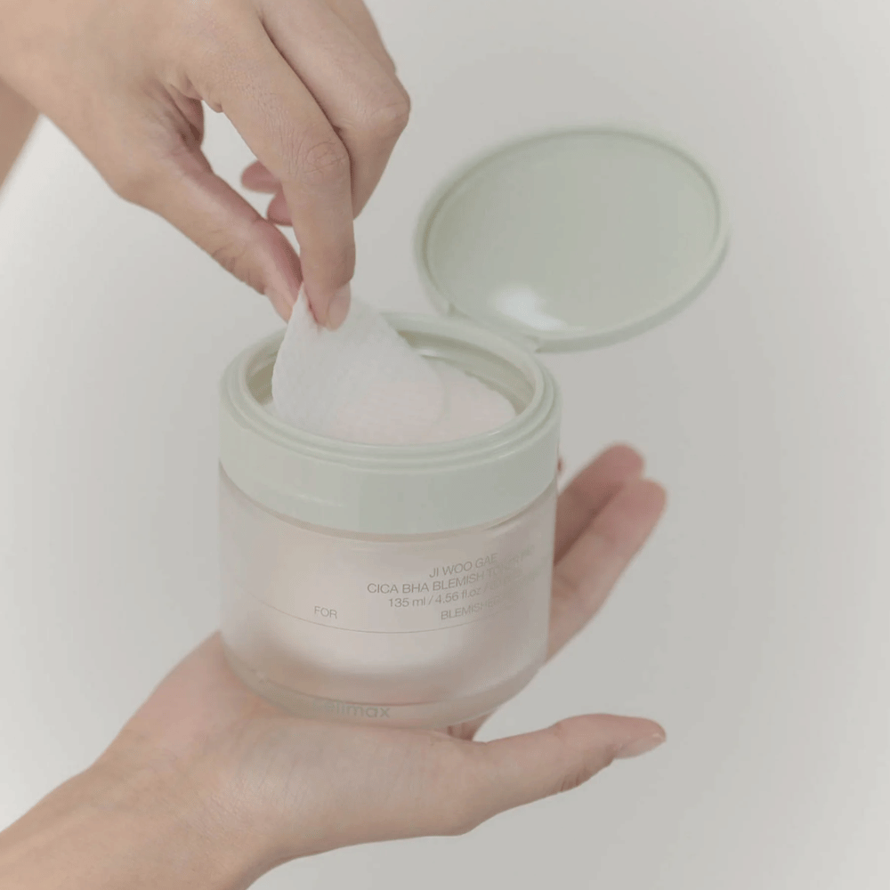 Roka vzame toner blazinico iz posode Celimax Ji Woo Gae Cica BHA Blemish Toner Pad, popolno za nečisto kožo.