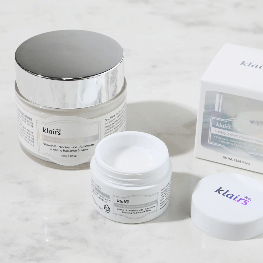 Zbirka izdelkov za nego kože Klairs na marmorni klopi: zaprta posoda, odprta posoda s kremo in škatla z besedilom.