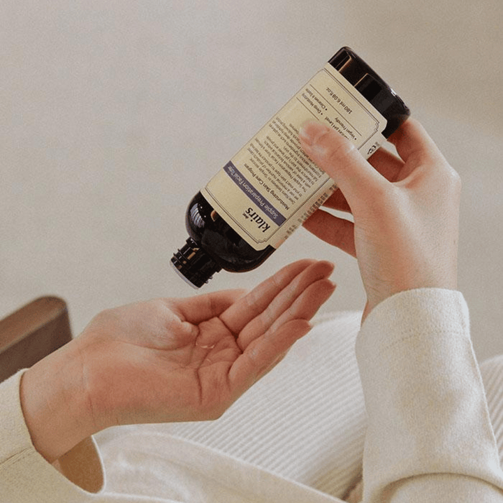 Oseba drži steklenico Klairs Supple Preparation Facial Toner obrnjeno navzdol nad svojo roko, pripravljena za doziranje izdelka.