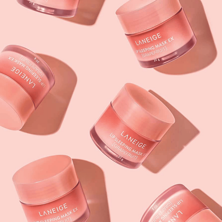 Štiri kozarčke LANEIGE Lip Sleeping Mask Grenivka 20g na roza ozadju, spodbuja grenivko in vlaženje.