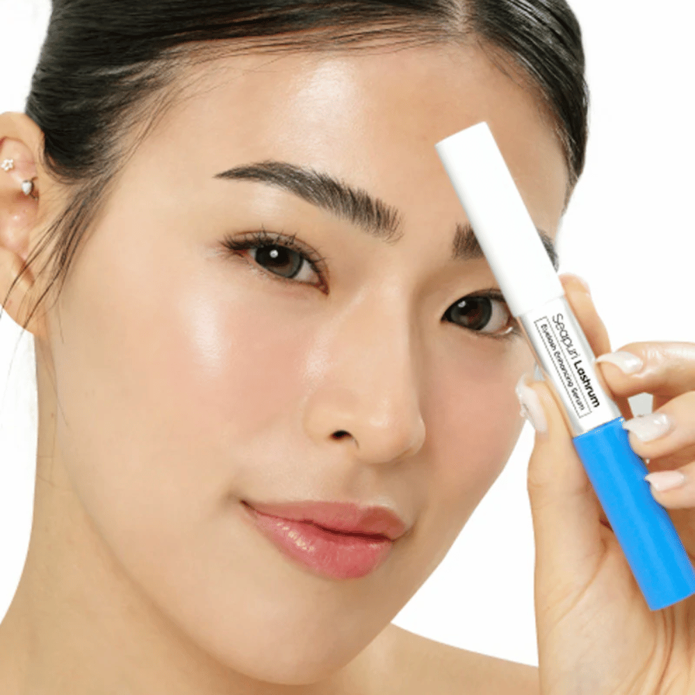 Ženska drži Seapuri Lashrum Eyelash Enhancing Serum. Negovalni serum za trepalnice, ki krepi in definira trepalnice.