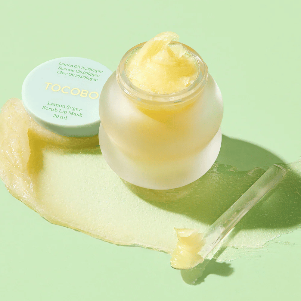 Odprta posoda z Tocobo Lemon Sugar Scrub Lip Mask na zeleni podlagi, z vsebino jasno vidno.