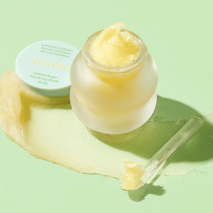 Odprta posoda z Tocobo Lemon Sugar Scrub Lip Mask na zeleni podlagi, z vsebino jasno vidno.