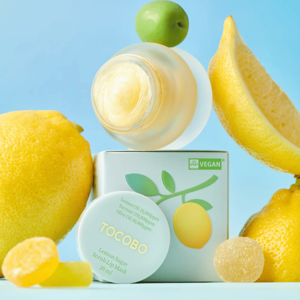 Posoda Tocobo Lemon Sugar Scrub Lip Mask, nameščena med limonami in embalažo, označena kot veganska.