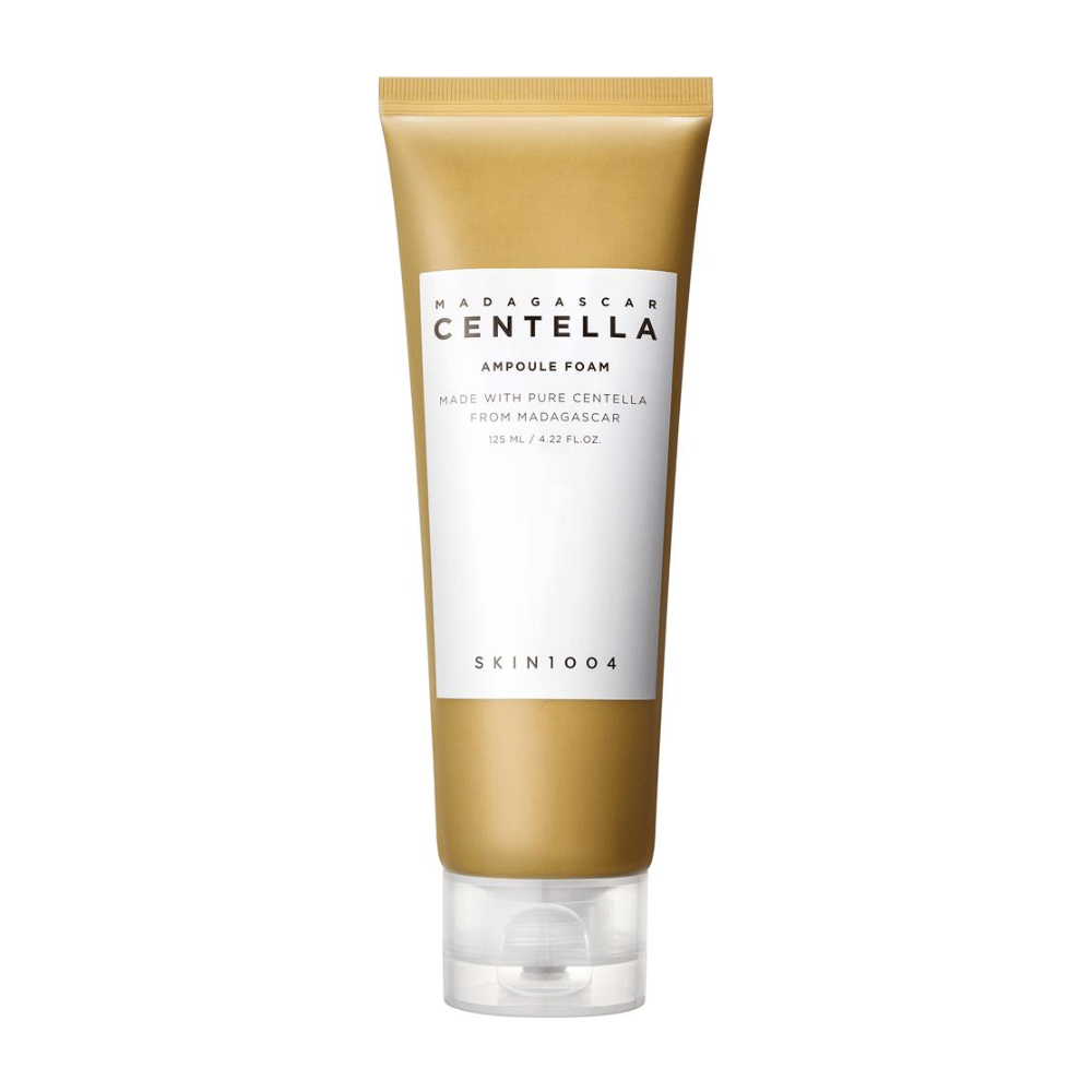 Slika prikazuje tubo "Madagascar Centella Ampoule Foam" znamke SKIN1004. To je čistilni izdelek za obraz, ki vsebuje 125 ml / 4.22 fl.oz. Formula temelji na čisti Centelli, pridobljeni iz rastlin na Madagaskarju. Izdelek je zasnovan za nežno čiščenje in nego kože.