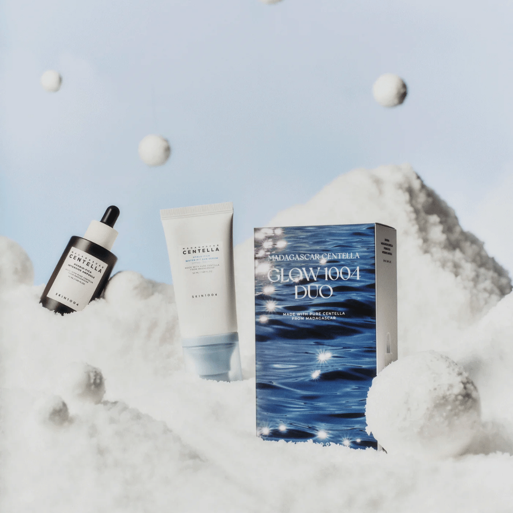 Slika prikazuje komplet za nego kože "Madagascar Centella Glow 1004 Duo" iz SKIN1004, postavljen na ozadje, ki prikazuje sneg in nebo.
