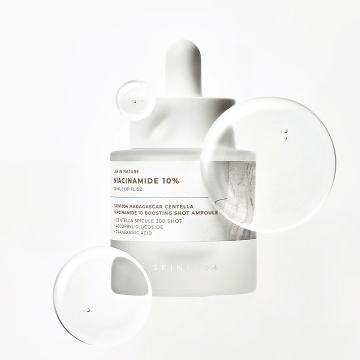 SKIN1004 Madagascar Centella Niacinamide 10 Boosting Shot Ampoule s serumski kapljicami, ki prikazujejo lahko, hitro vpijajočo formulo z niacinamidom, traneksaminsko kislino in centella.