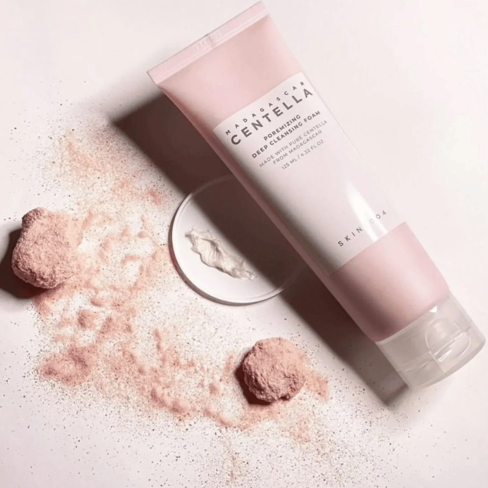 Madagascar Centella Poremizing Deep Cleansing Foam je predstavljen v roza tubi. Tuba leži na svetlem ozadju skupaj z roza prahom, ki daje občutek čistosti in svežine. Izdelek je zasnovan za globinsko čiščenje kože s pomočjo čiste centelle z Madagaskarja.