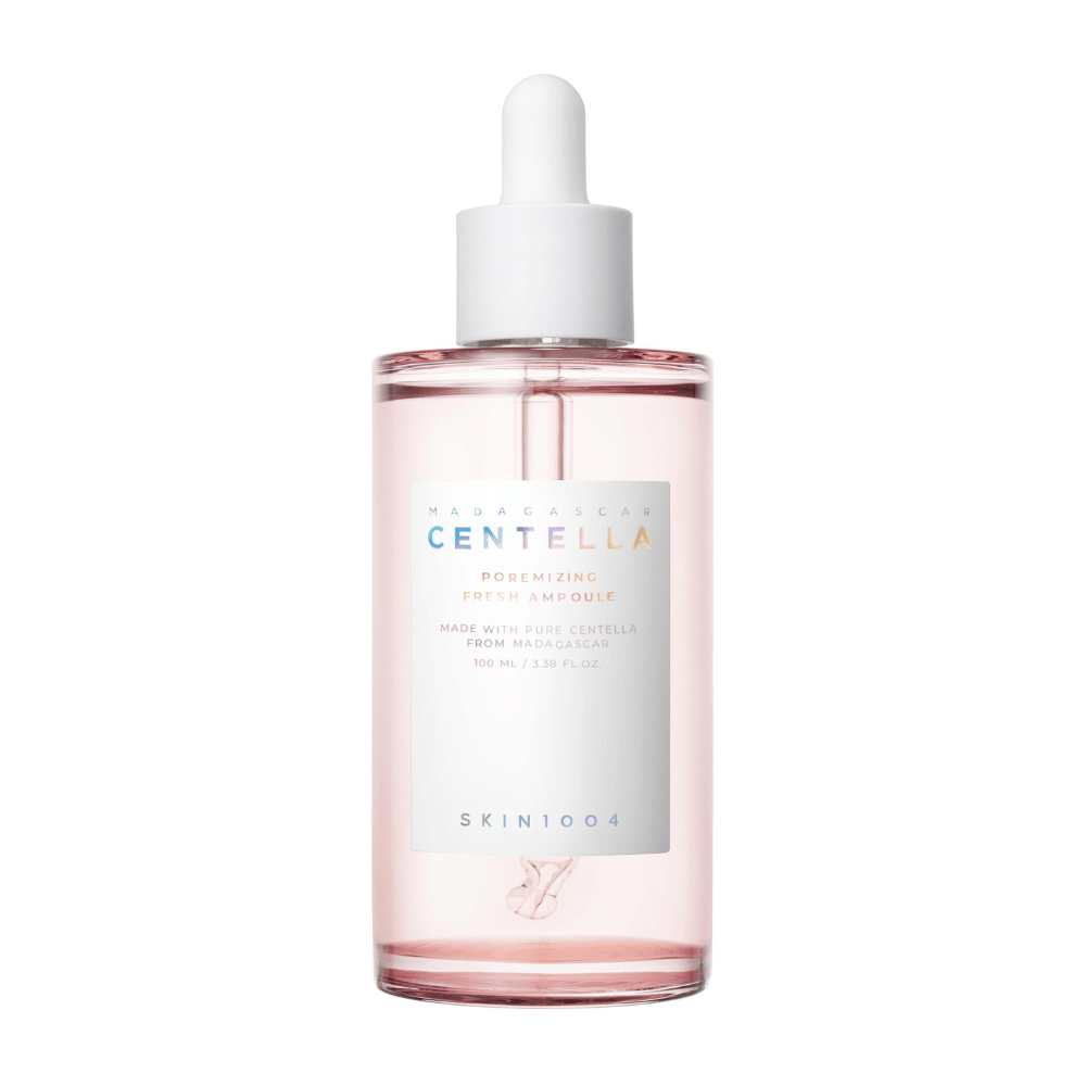 Prozorna steklenička z rožnato tekočino in belo kapalko, SKIN1004 Madagascar Centella Poremizing Fresh Ampoule, na beli podlagi.