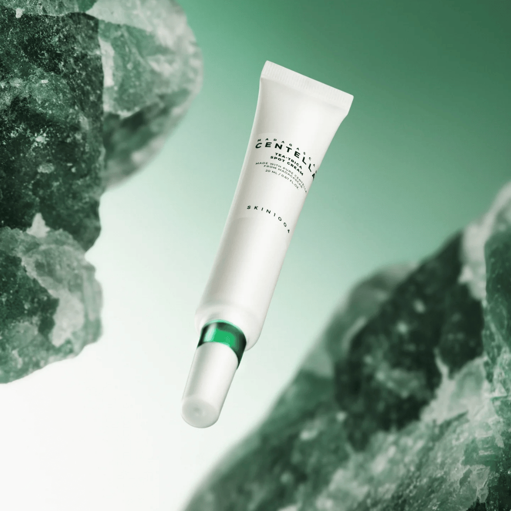 SKIN1004 Madagascar Centella Tea-Trica Spot Cream 20 ml proti aknam in mozoljem, slika izdelka z zelenim ozadjem in kristalno strukturo – pomirjujoč spot treatment s centello asiatica in tea tree.