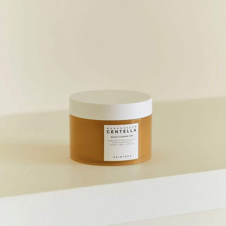 SKIN1004 Madagascar Centella Quick Calming Pad postavljena na beli polici – jantarna posoda z belim pokrovom in jasno etiketo spredaj.