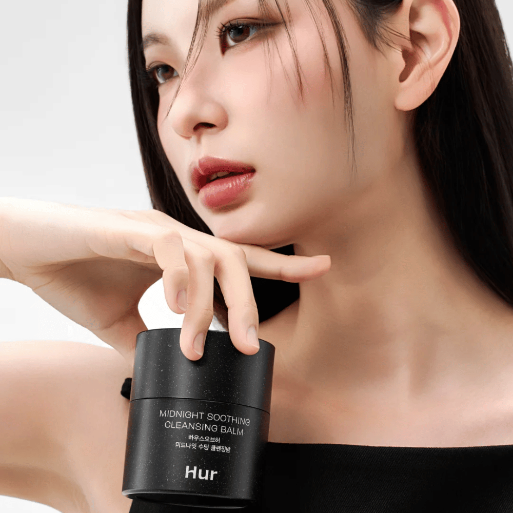 Model drži Kako Midnight Soothing Cleansing Balm. Korejski čistilni balzam, ki učinkovito odstranjuje ličila in čisti kožo brez draženja.