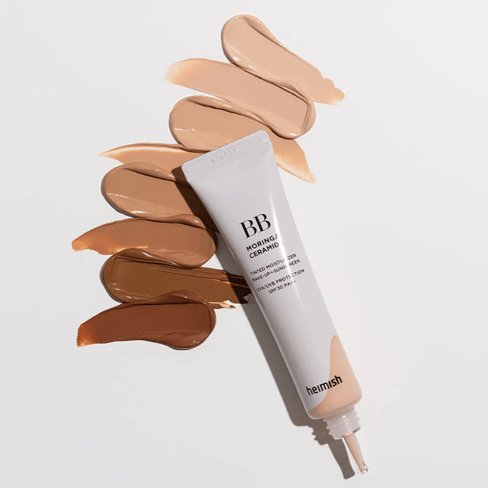 Heimish Moringa Ceramide BB Cream obkrožen z več vzorci odtenkov v različnih tonih kože. Slika prikazuje široko barvno paleto izdelka in kremasto teksturo, ki zagotavlja naravno prekrivnost in enakomeren ten kože.