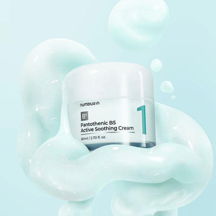 Numbuzin No.1 Pantothenic B5 Active Soothing Cream 80 ml v svetlo zeleni posodi z belim pokrovom, obdana z mehkimi valovi svetlo zelene kremaste teksture na svetlo modrem ozadju.