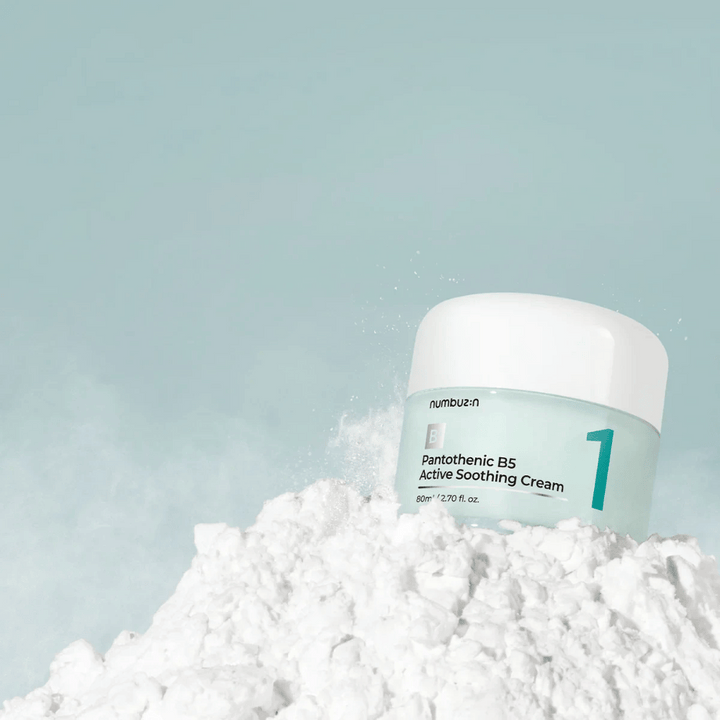 Numbuzin No.1 Pantothenic B5 Active Soothing Cream 80 ml v svetlo zeleni posodi z belim pokrovom, postavljena na kup belega prahu na svetlem ozadju.