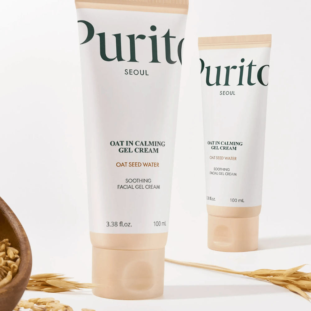Purito Oat-In Calming Gel Cream v bež tubi, postavljena z zrni ovsa. Pomirja občutljivo kožo z ovseno vodo in lahko gel teksturo.