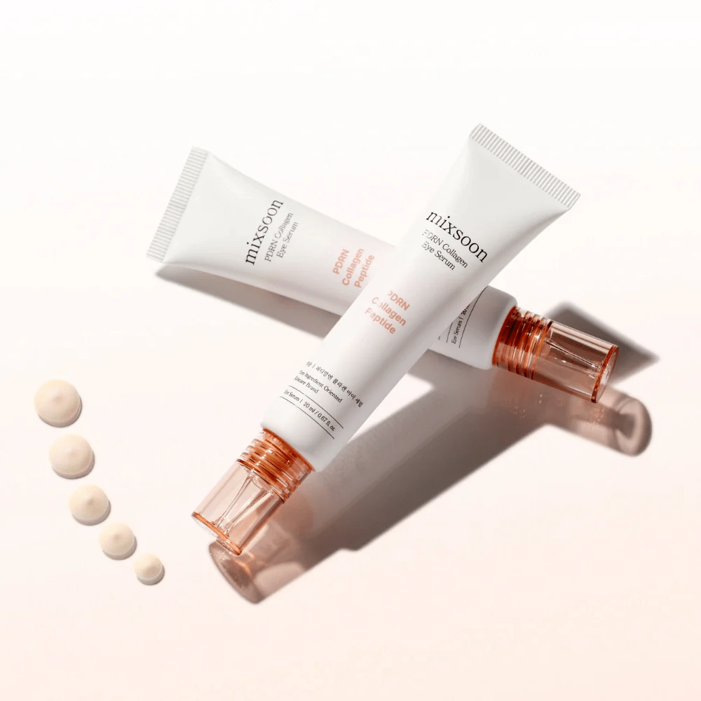 Dve tubi Mixsoon PDRN Collagen Eye Serum sta prekrižani z majhnimi kapljicami seruma. Lahka nega za oči, ki vlaži in izravnava linije.