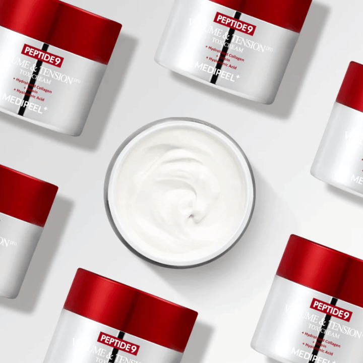 Več posod MEDI-PEEL Peptide 9 Volume & Tension Tox Cream, razporejenih na beli podlagi. Izdelek intenzivno vlaži in daje koži volumen in sijaj.