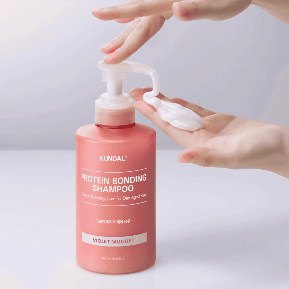 Roka iztisne KUNDAL Protein Bonding Shampoo Violet Muguet v kremasti konsistenci, obnovitveni šampon za poškodovane lase.