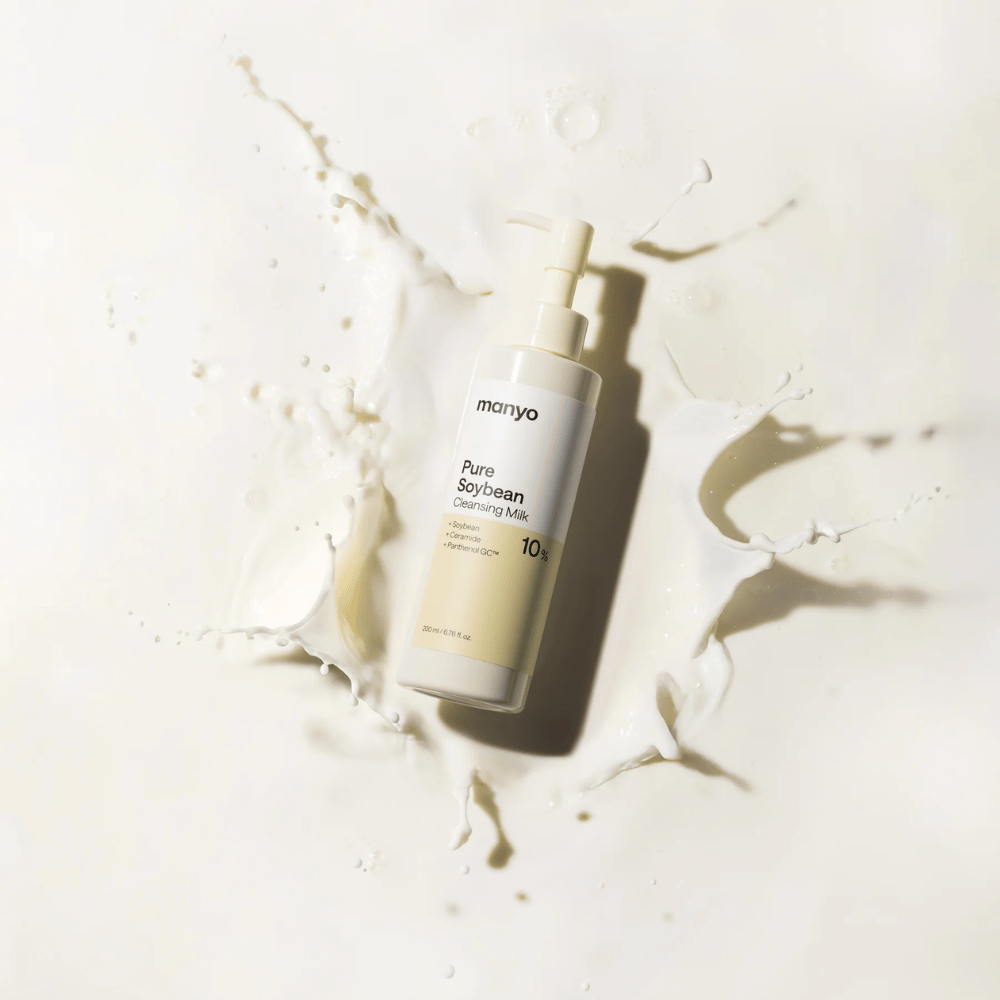 1. Ma:nyo Pure Soybean Cleansing Milk – nežno čistilno mleko s sojo v plastenki s pumpico, obdani z mlečnimi kapljicami na svetlem ozadju