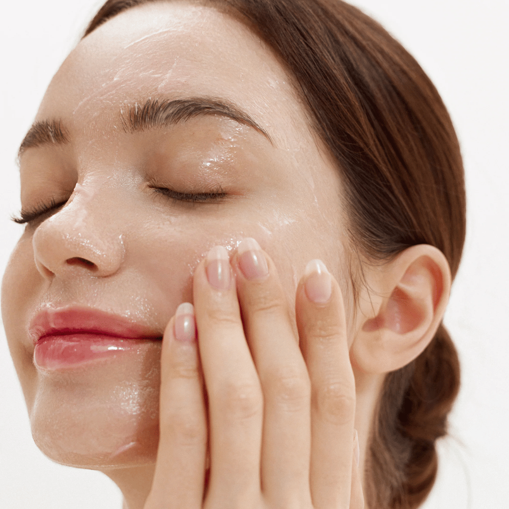 Kako se Purifying Cleansing Balm nanaša na obraz. Kremni balzam, ki se stopi ob stiku s kožo in nežno odstrani umazanijo, zaščito pred soncem in ličila.