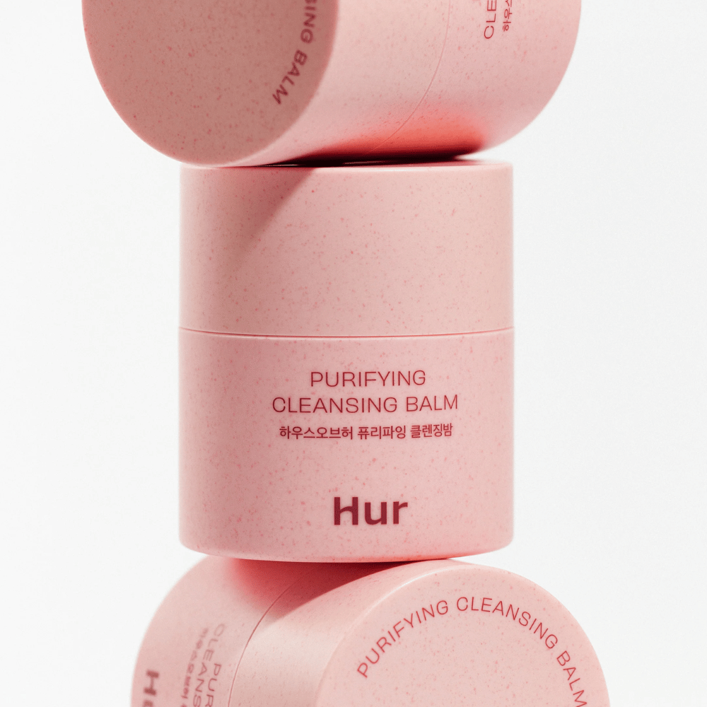 Kako Purifying Cleansing Balm v roza embalaži, zloženi v studiu. Čistilni balzam, ki učinkovito raztopi ličila, sebum in nečistoče, ne da bi izsušil kožo.