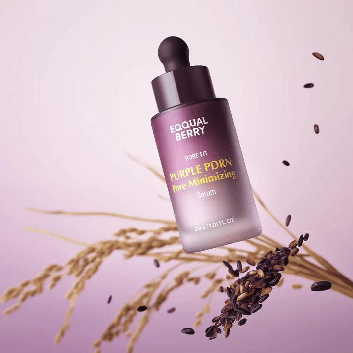Steklenička z Equal Berry Purple PDRN Pore Minimizing Serum lebdi na vijoličnem ozadju, obdana s črnimi riževimi zrni in riževimi stebli.