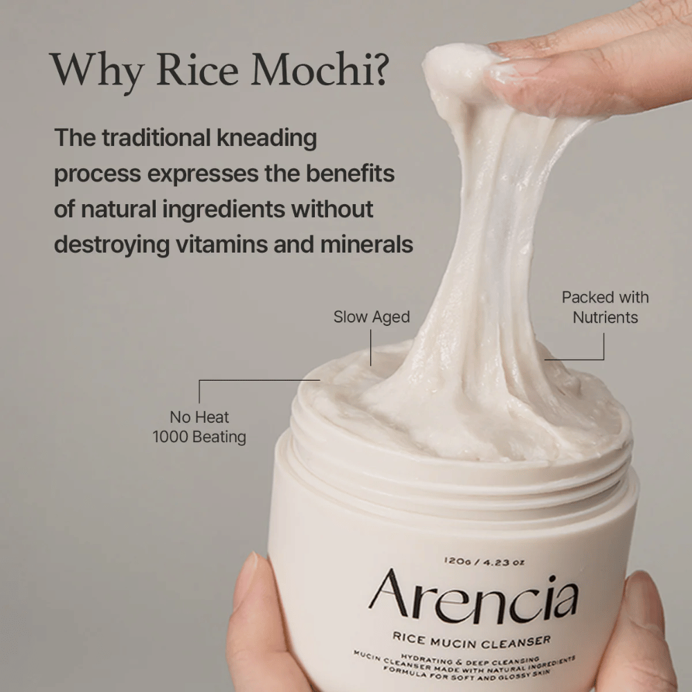 Roka, ki dviguje elastično, belo čistilno kremo iz posode z oznako "Arencia Rice Mucin Cleanser". Besedilo opisuje tradicionalno gnetenje, ki ohranja hranilne snovi, ne da bi uničilo vitamine in minerale.