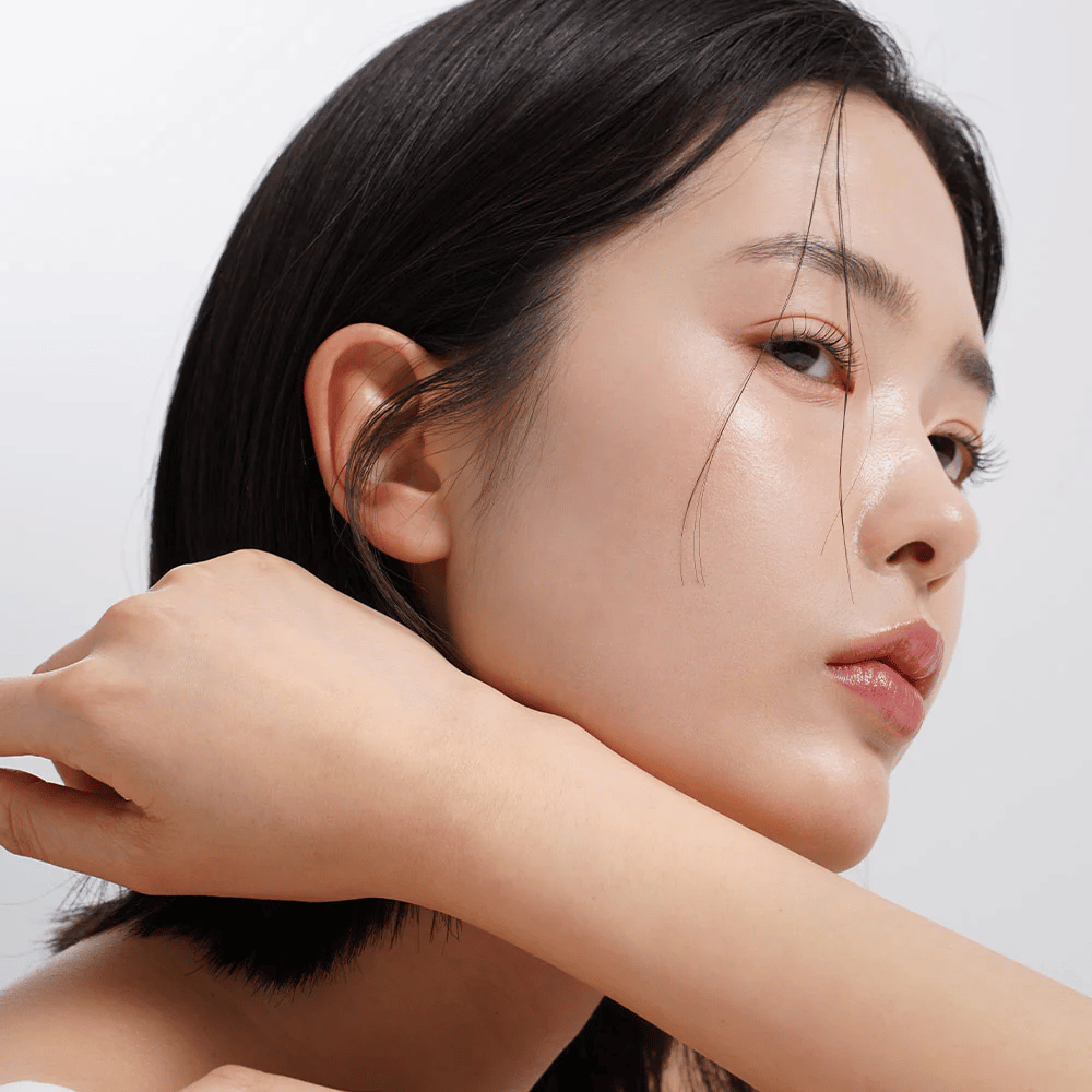 Bližnji posnetek ženske z enakomerno, sijočo kožo in naravnim sijajem. Popolna navdih za nego kože za svežo in navlaženo polt.