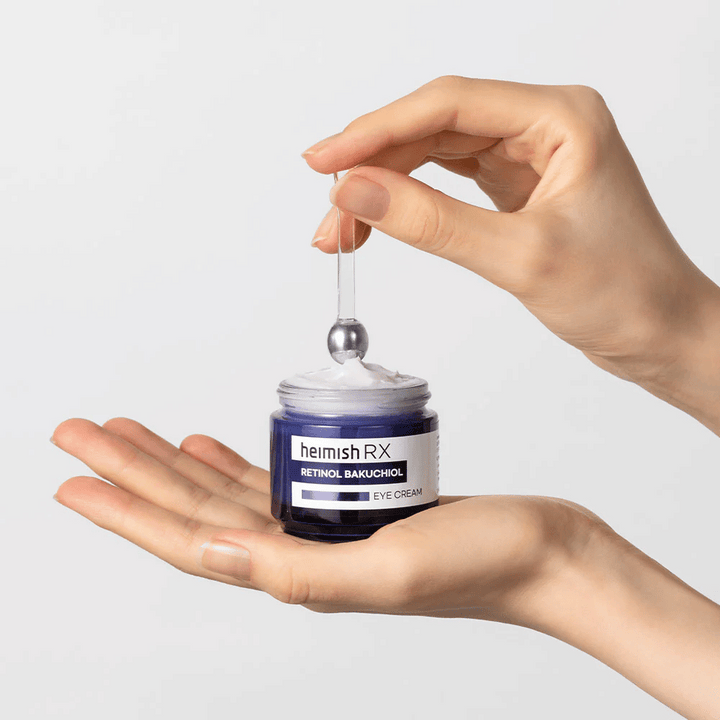 Heimish RX Retinol Bakuchiol Eye Cream v elegantnem modrem lončku, dvignjena z metalnim aplikatorjem. Krema za oči z retinolom in bakuchiolom za zmanjšanje drobnih linij in čvrstejšo kožo.