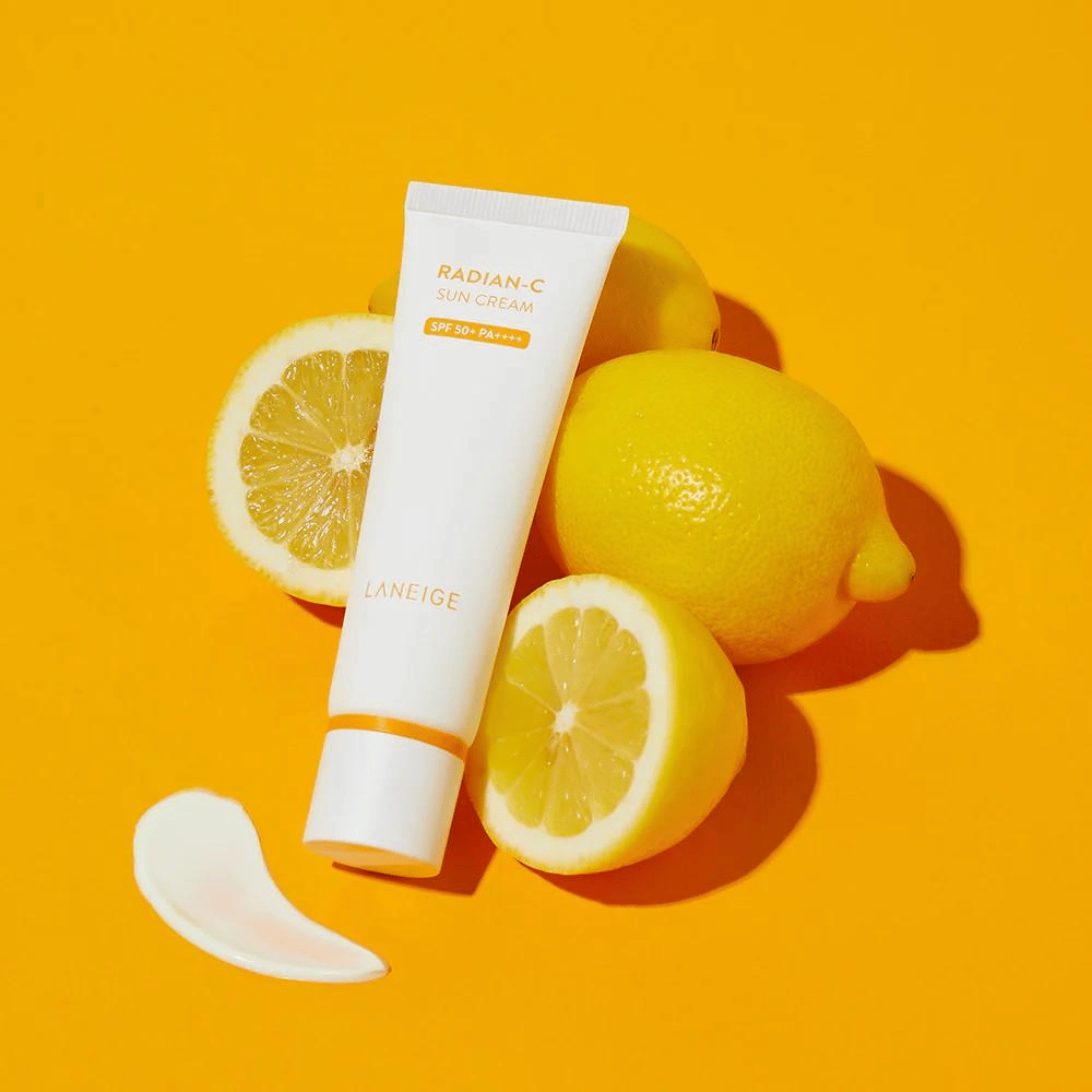 LANEIGE Radian-C Sun Cream SPF 50+ PA++++ z limonami in kančkom kreme za sončenje na živahni rumeni podlagi.